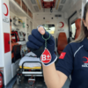 Ambulansta NFC Kan Grubu Anahtarlığı Kullanımı Ambulansın içinde tıbbi ekipmanların ve sedyenin önünde duran Türk Kızılay üniformalı bir sağlık görevlisi, elinde B+ pozitif kan gruplu kırmızı NFC akıllı anahtarlığı tutarak gösteriyor.