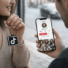 Bir kişinin TikTok profili açık telefonu tuttuğu, diğer kişinin TikTok logolu NFC anahtarlık gösterdiği sosyal medya etkileşim sahnesi.